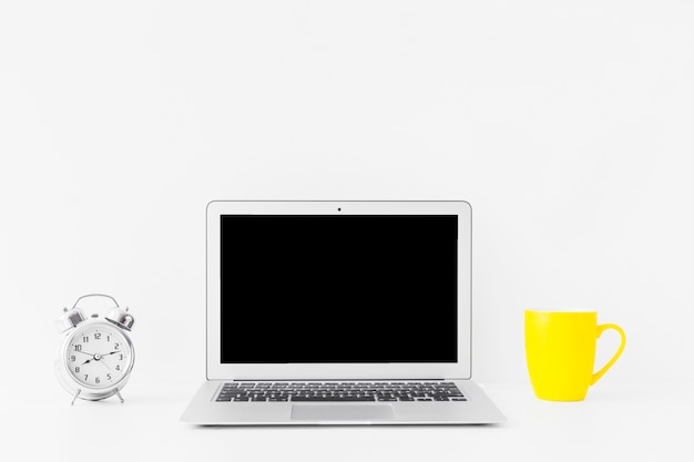 White workspace with laptop and yellow mug