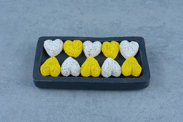 White and yellow cookies on the board , on the marble table. 