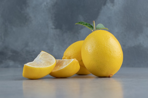 Целые и нарезанные лимоны на мраморе