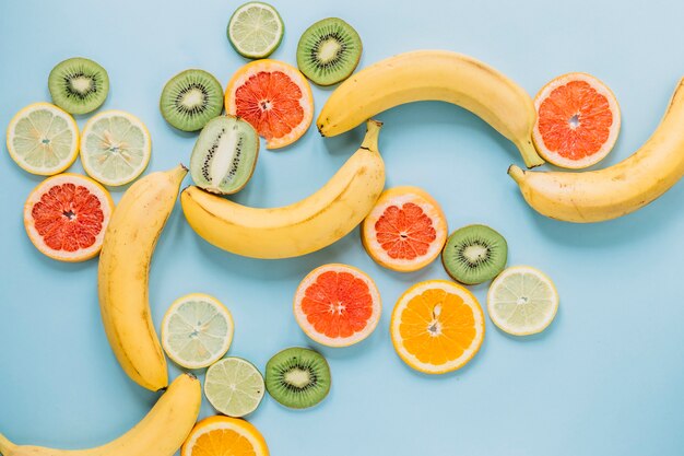 Whole bananas near sliced fruits