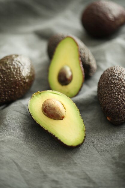 Whole and cut avocados on gray cloth