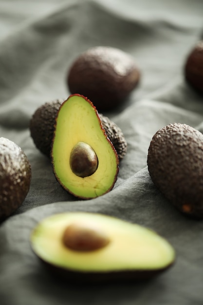 Avocado interi e tagliati su panno grigio