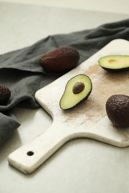 Whole and cut avocados on wooden cutting board