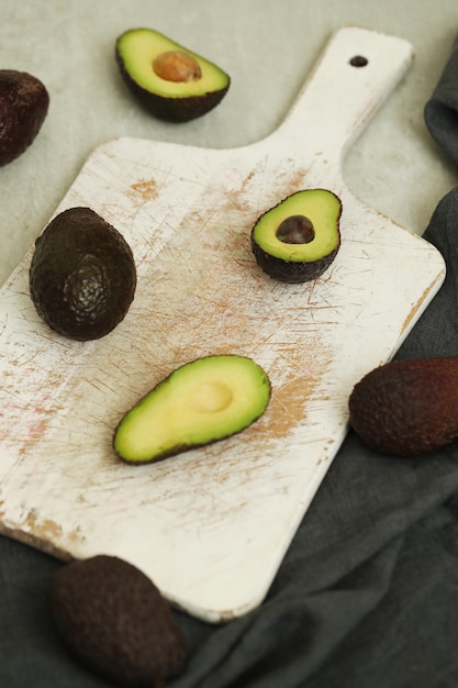 Free photo whole and cut avocados on wooden cutting board
