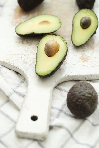 Whole and cut avocados on wooden cutting board