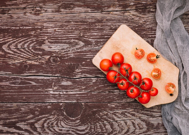 Whole and cut cherry tomatoes on chopping board over the desk