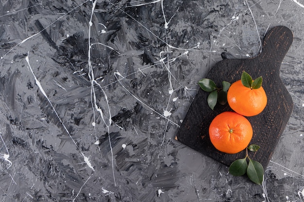 Whole fresh orange fruits with leaves placed on black board.