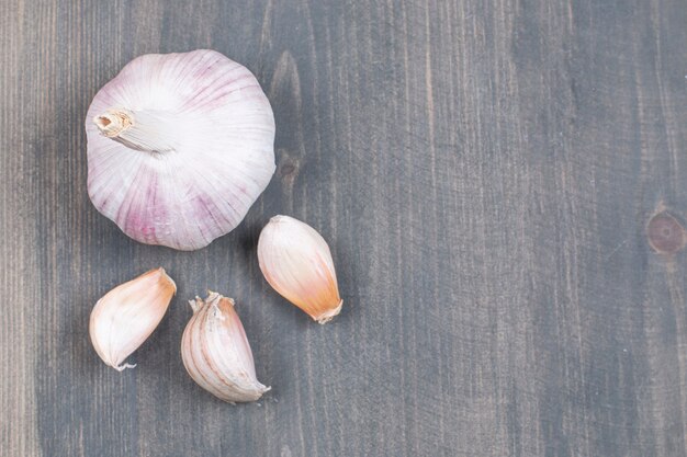 Whole garlic and cloves on wooden surface