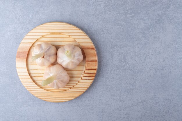 Free photo whole garlic in wooden plate