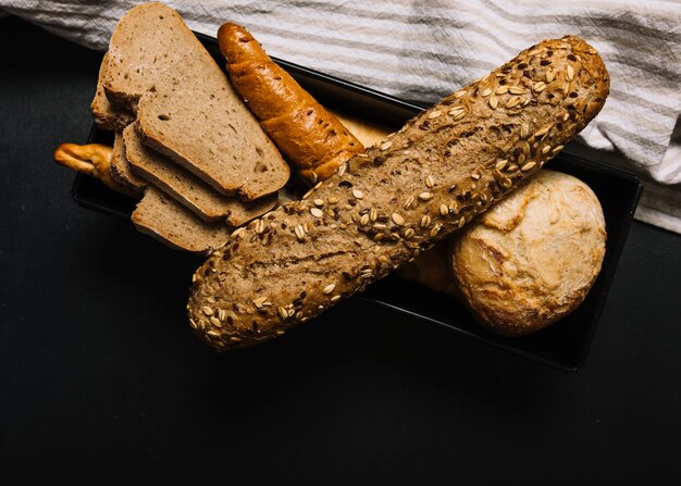 Whole grain bread with slice on dark backdrop