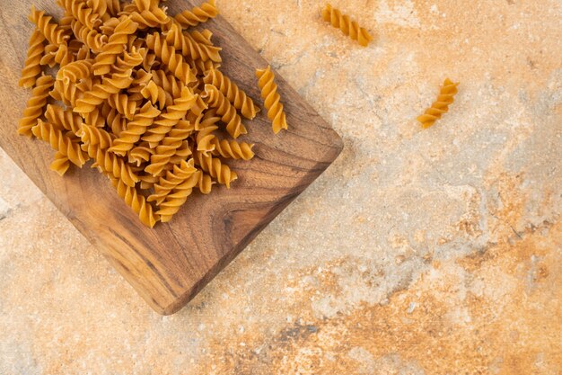 Whole grain pasta fusilli on a board , on the marble.