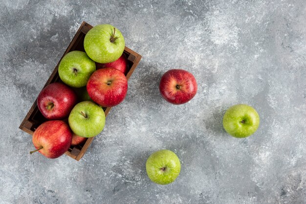 Whole green apples and cinnamon sticks on marble table.