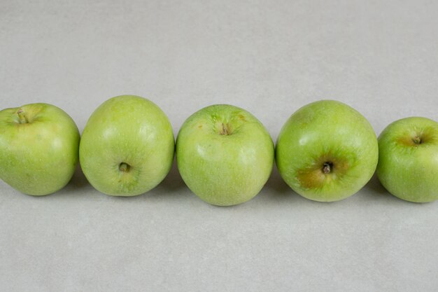 Whole green apples on gray surface