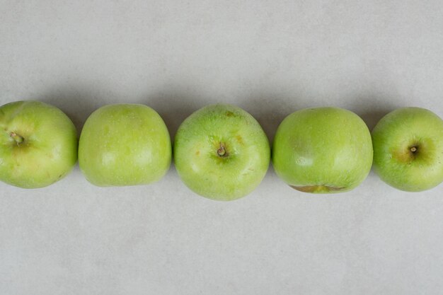 Whole green apples on gray surface