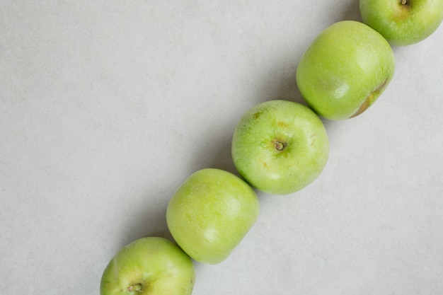 Whole green apples on gray surface