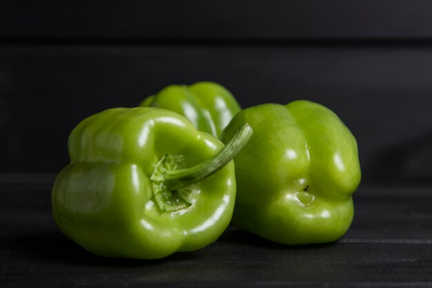 Whole green bell peppers placed on wooden dark table . High quality photo