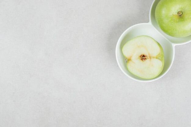 Free photo whole and half cut green apples in white bowls