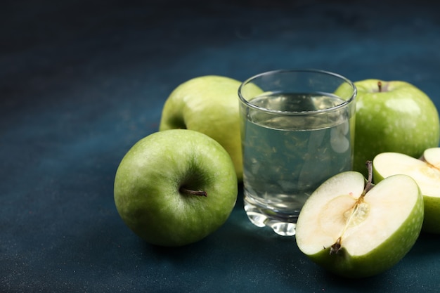 Whole and half cut green apples with a glass of apple juice.