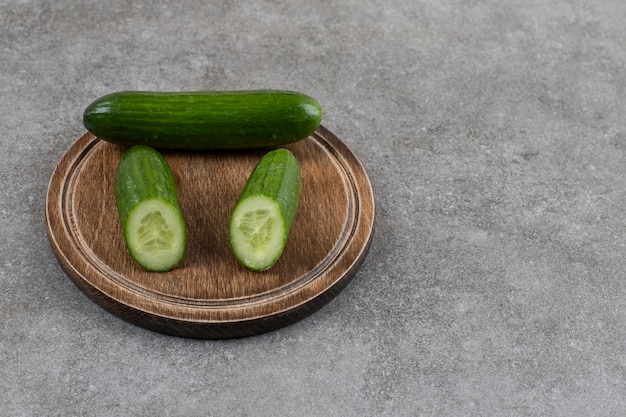 Foto gratuita di cetrioli sani interi o tagliati a metà su tavola di legno.