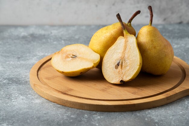 Whole and half pears on a wooden board.