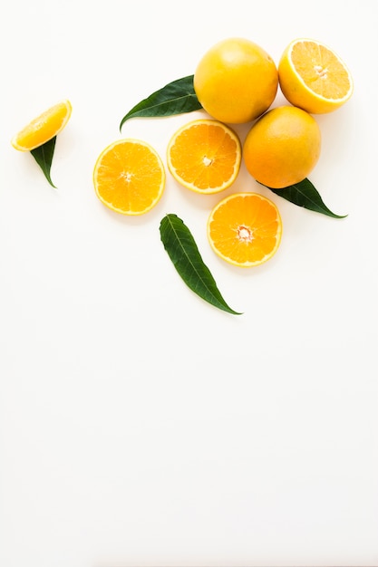An whole and halved oranges with green leaves isolated on white background
