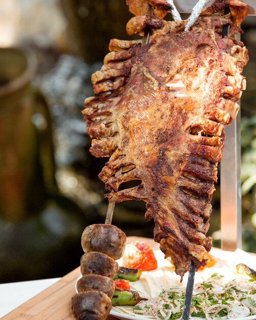 Whole lamb ribs kebab and grilled potatoes on steel skewers