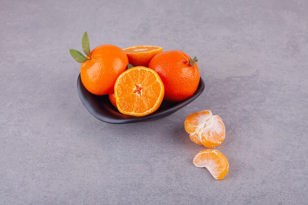 녹색 잎을 가진 전체 오렌지 과일 접시에 배치.