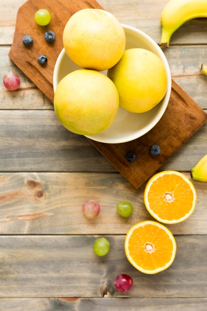 Whole oranges; grapes; banana and blueberries on wooden backdrop