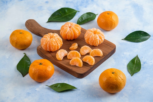 Whole and peeled slice of clementine mandarins. Over wooden board