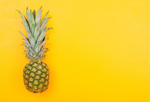 Whole pineapple on a yellow. top view.