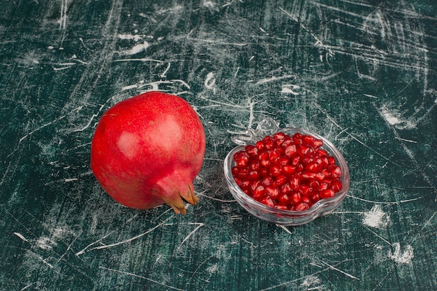 Free photo whole pomegranate and seeds on marble table.