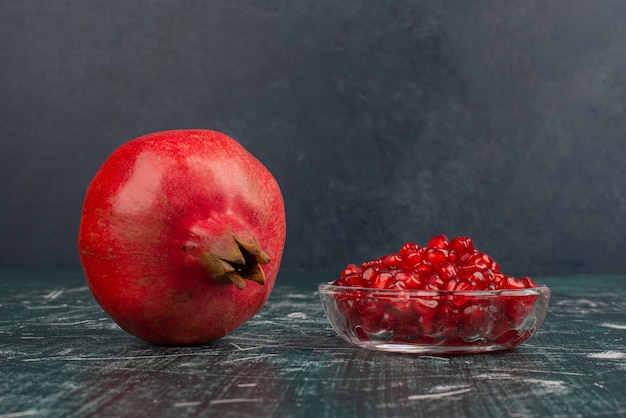 Whole pomegranate and seeds on marble table.