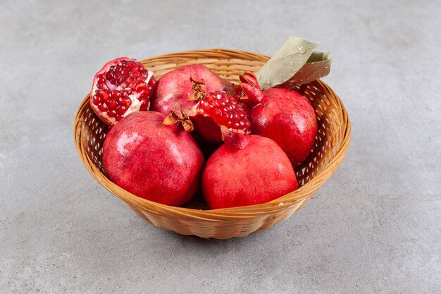 Whole pomegranates and seeds in wooden basket