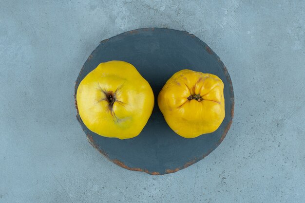 Whole quinces on a board , on the marble background. High quality photo