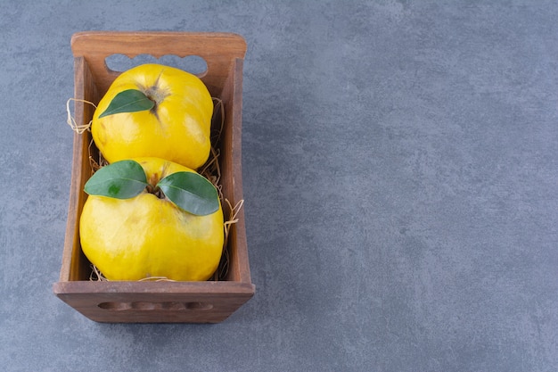 Whole quinces in a box on the dark surface