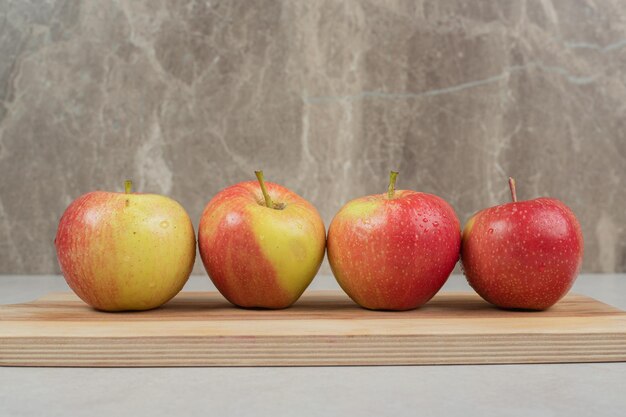 Free photo whole red apples on wooden board.