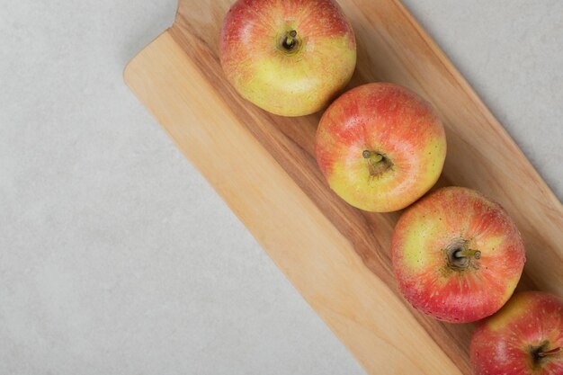 Whole red apples on wooden board