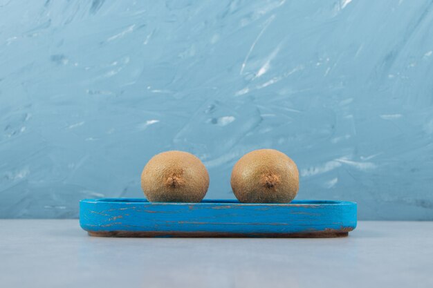 Whole ripe kiwis on blue plate. 