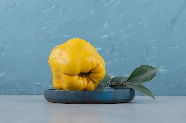 Whole ripe quince on blue plate