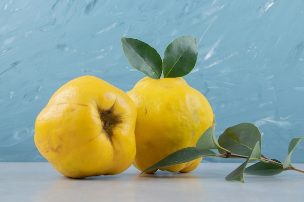 Free photo whole ripe quinces with leaves on blue surface