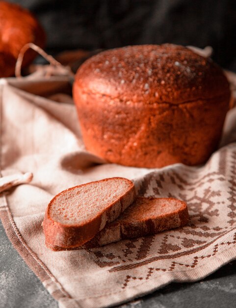 Whole round bread with thin slices on a white tablecloth 