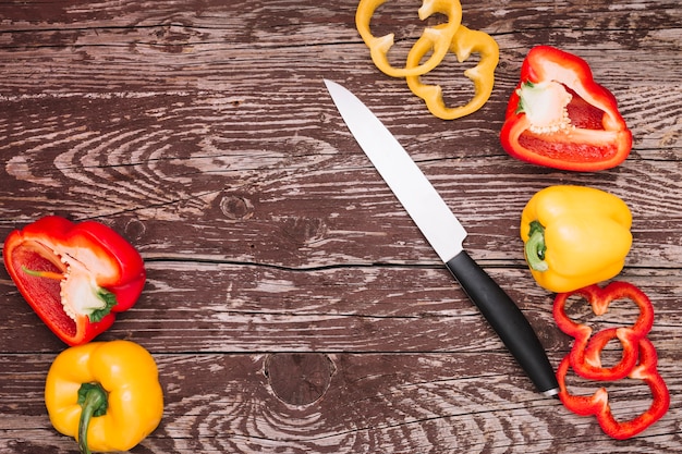 Whole; slice and halved fresh bell pepper with sharp knife on wooden table