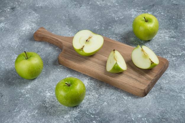 Whole and sliced apples on wooden board.