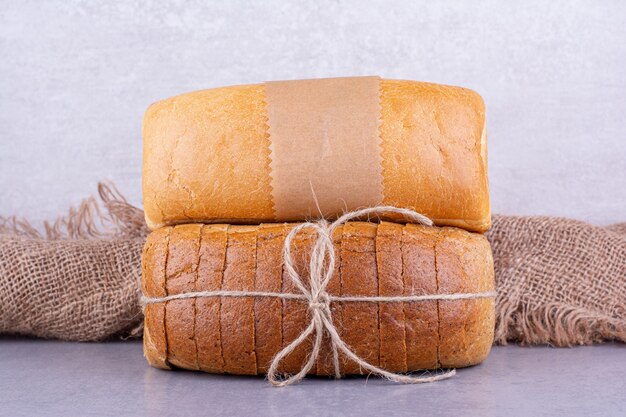 Whole and sliced blocks of bread on marble surface