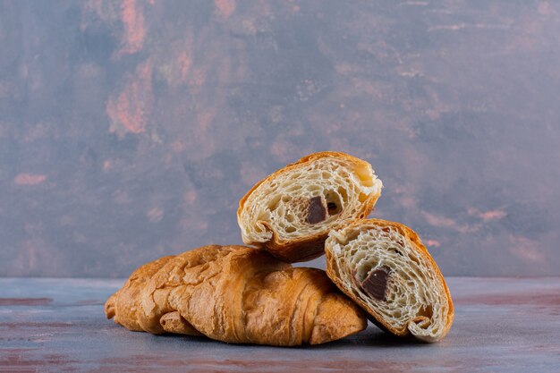 Whole and sliced croissants , on the marble background.