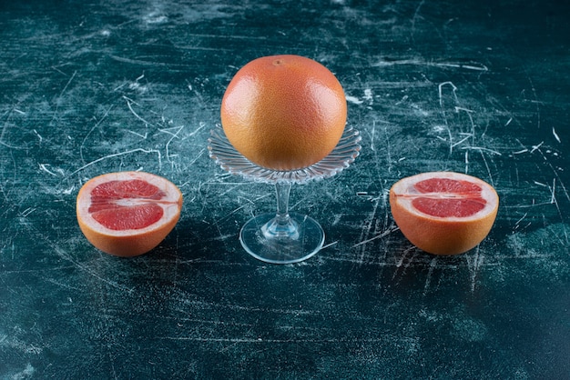 Whole and sliced grapefruits on marble table. 