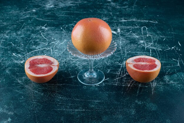 Whole and sliced grapefruits on marble table. 