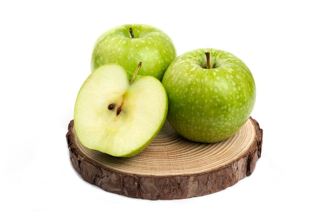 Целые и нарезанные зеленые яблоки на деревянной доске на белом.