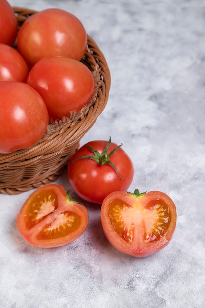 Whole and sliced juicy red tomatoes placed on marble