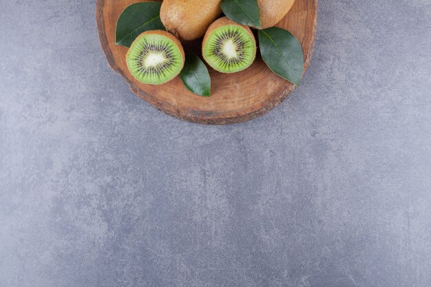 Whole and sliced kiwi fruit placed on a stone table.
